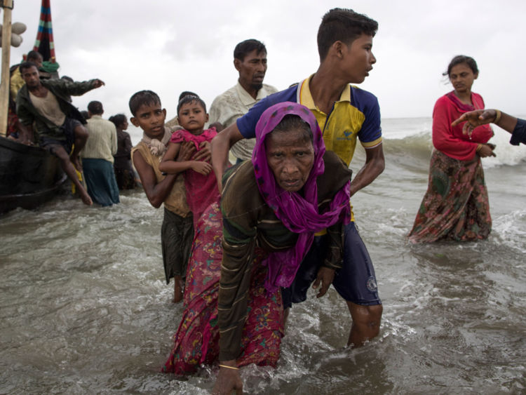  Un homme Rohingya aide une femme âgée hors de l'eau après son arrivée à Dakhinpara, au Bangladesh 