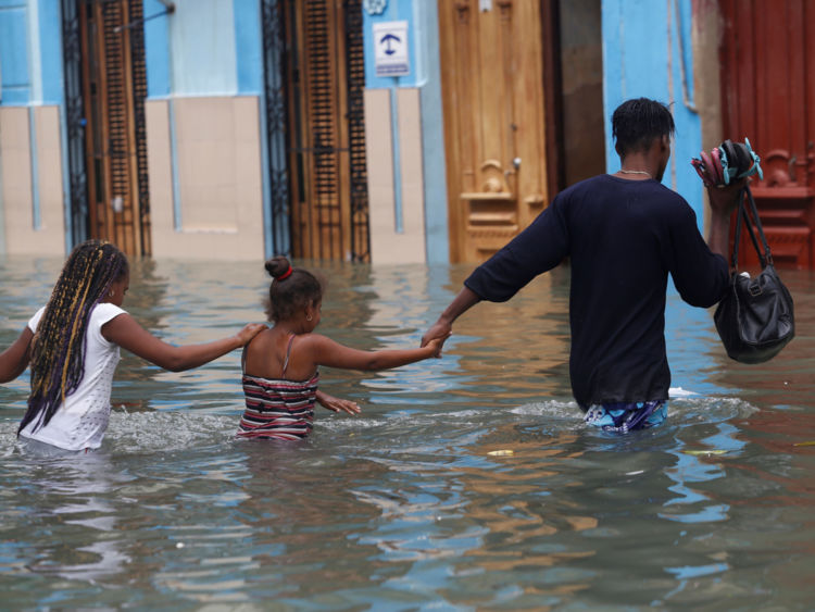  Un homme traverse une rue inondée de la Havane avec ses enfants 