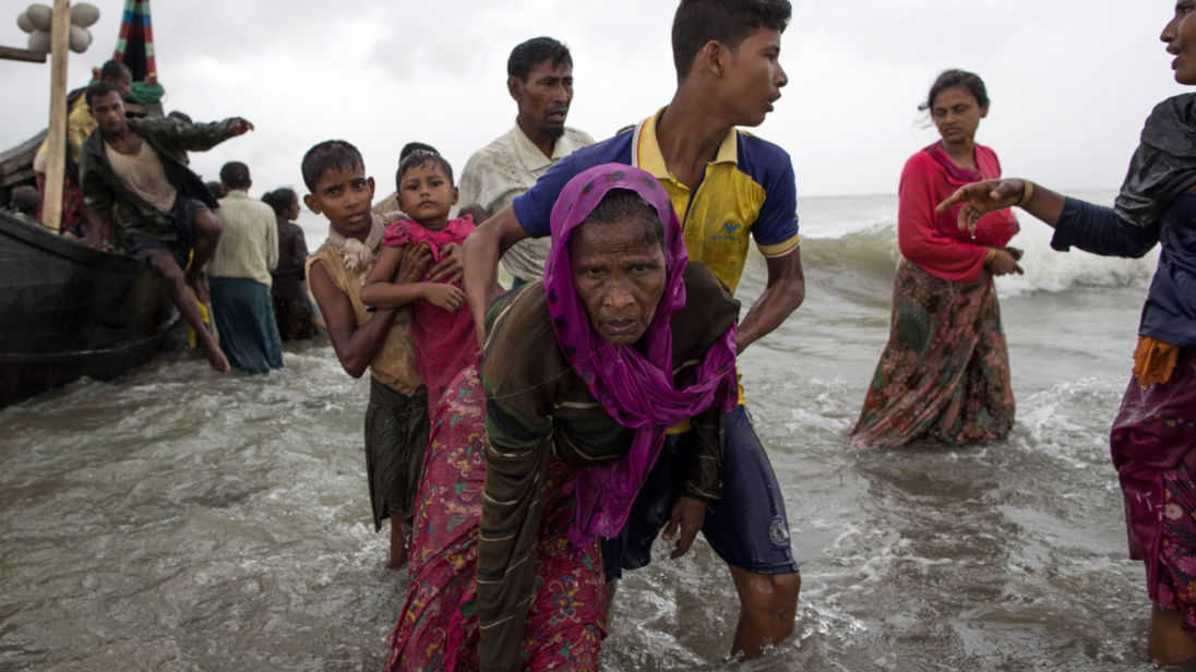 Un homme Rohingya aide une femme âgée hors de l'eau après son arrivée à Dakhinpara, Bangladesh 