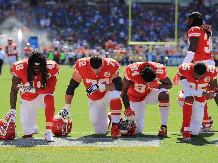  Terrance Smith # 48, Eric Fisher # 72, Demetrius Harris # 84, et Cameron Erving # 75 des Kansas City Chiefs est vu prendre un genou 
