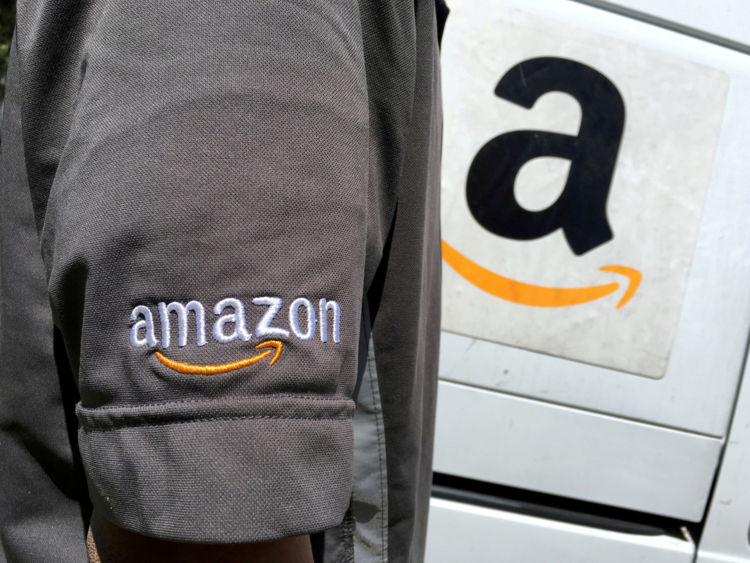  Un pilote Amazon.com Inc se trouve à côté d'un camion de livraison Amazon à Los Angeles, Californie, États-Unis, le 21 mai 2016 