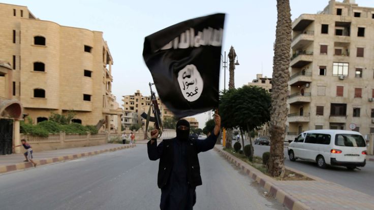  Un membre fidèle à l'ISIL brandit un drapeau de l'EIIL à Raqqa, en Syrie 