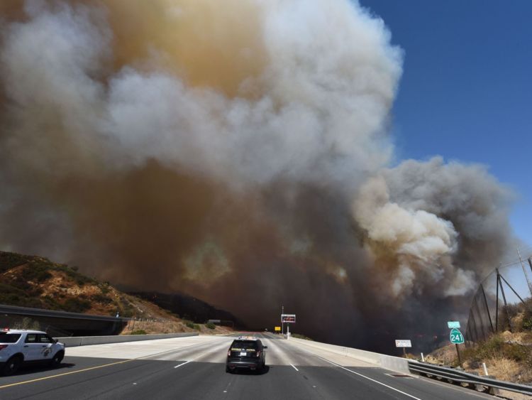  Une voiture de police bloque l'autoroute 241 alors que la fumée du Canyon 2 Fire couvre l'autoroute près d'Orange, en Californie, le 9 octobre 2017 à Orange, en Californie 