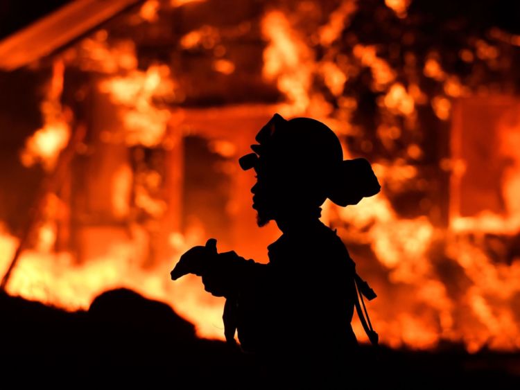  Un pompier détenu surveille les flammes pendant qu'une maison brûle dans la région vinicole de Napa, en Californie, le 9 octobre 2017, alors que de nombreux incendies provoqués par le vent continuent de fouetter la région 