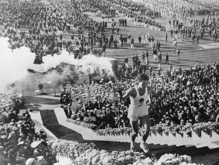  Le porte-flambeau de la flamme olympique Yoshinori Sakai monte les marches pour allumer le chaudron lors de la cérémonie d'ouverture des Jeux olympiques d'été au stade olympique national de Tokyo, le 10 octobre 1964 
