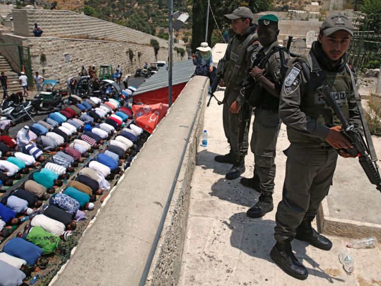  Les forces de sécurité israéliennes montent la garde alors que les fidèles musulmans palestiniens prient devant la Porte des Lions, une entrée principale de la mosquée Al-Aqsa dans la vieille ville de Jérusalem 