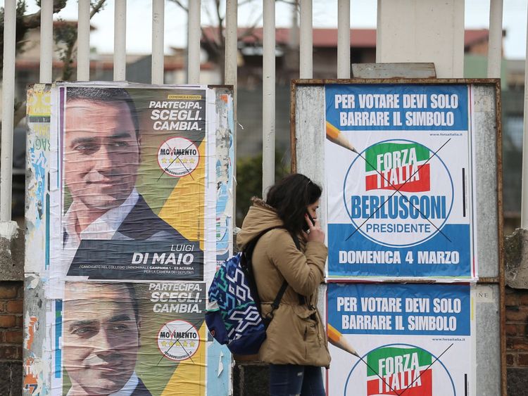  Une femme passe des affiches électorales à Naples avant l'ouverture du scrutin 