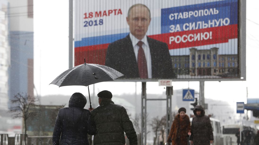  Les gens marchent à côté de l'affiche de la campagne électorale du président russe Vladimir Poutine à Stavropol, en Russie, le 14 mars 2018. Le tableau se lit comme suit 