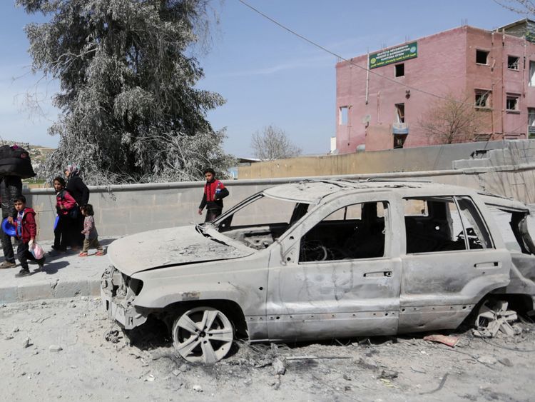  Une famille marche avec tous les effets personnels qu'elle peut transporter en évacuant Afrin à côté d'une voiture usée 