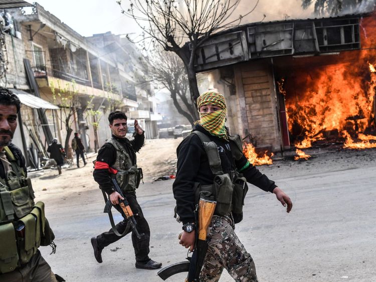  Les rebelles syriens soutenus par la Turquie passent devant un magasin en feu à Afrin 