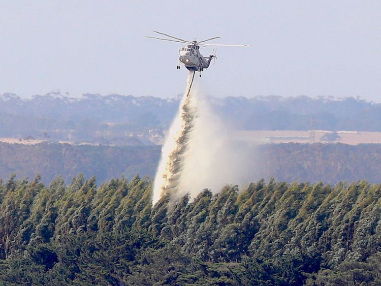  Un hélicoptère laisse tomber de l'eau sur une forêt Des feux de brousse brûlent à proximité, à la périphérie de la ville de Cobden, au sud-ouest de Melbourne, en Australie, le 18 mars 2018 