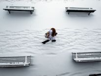  Une femme passe devant des bancs couverts de neige dans un Parc à Lausanne, Suisse 