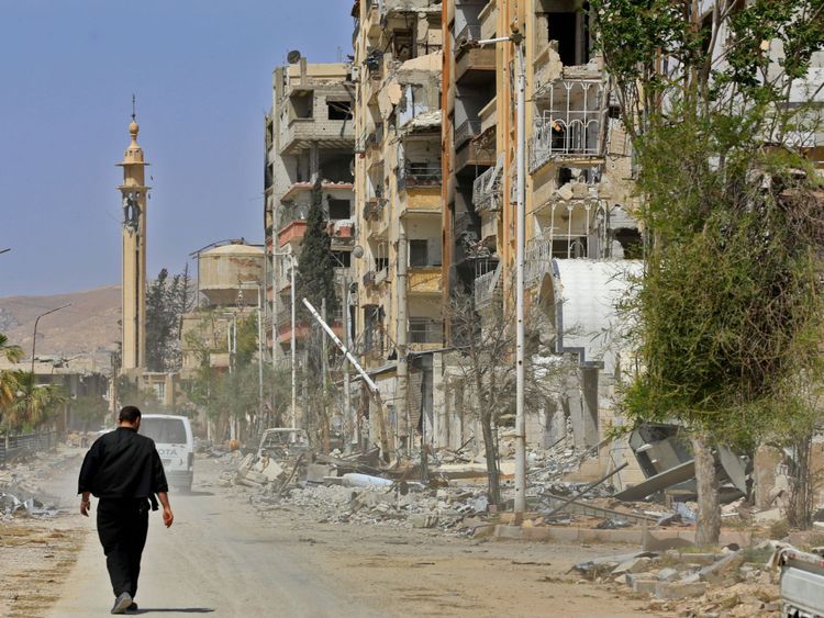  Une photo prise lors d'une tournée organisée par l'armée syrienne le 20 avril 2018 montre un homme marchant dans une rue Ghouta, ville de Douma à la périphérie de la capitale Damas 