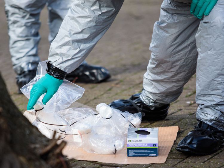  Les policiers en tenue de protection et les masques recueillent des échantillons près du banc où ils ont été trouvés 