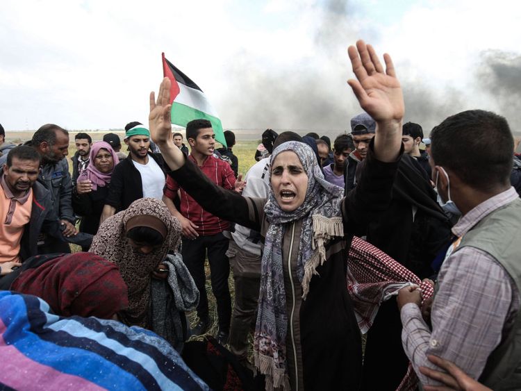  Les manifestants palestiniens brandissent leur drapeau et leur geste pendant une manifestation commémorant le Jour de la Terre près de la frontière avec Israël, à l'est de Khan Yunis, au sud de la bande de Gaza le 30 mars 2018 