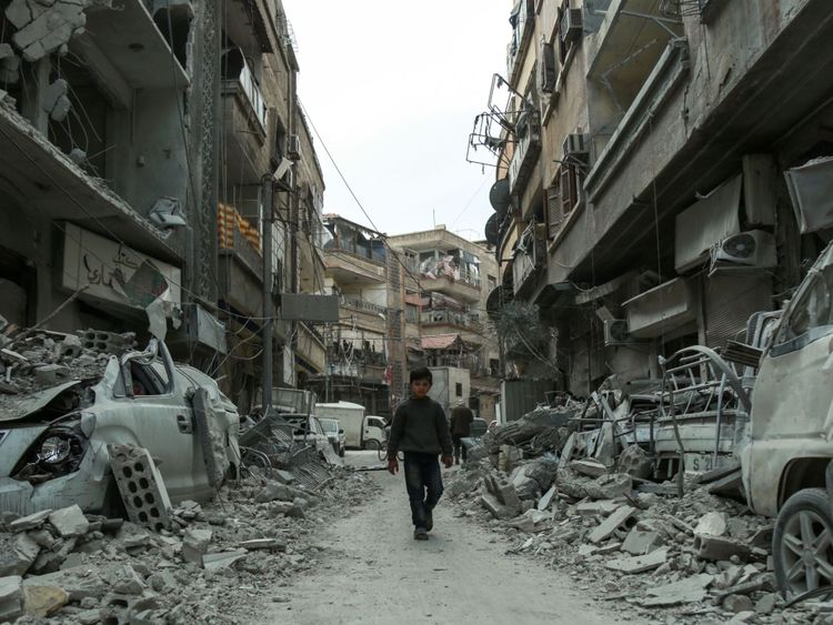  Une photo prise le 8 mars 2018 montre un chi syrien ld marchant dans une rue au-dessus des décombres des bâtiments détruits, dans la ville rebelle de Douma dans l'enclave de la Ghouta orientale à la périphérie de Damas 