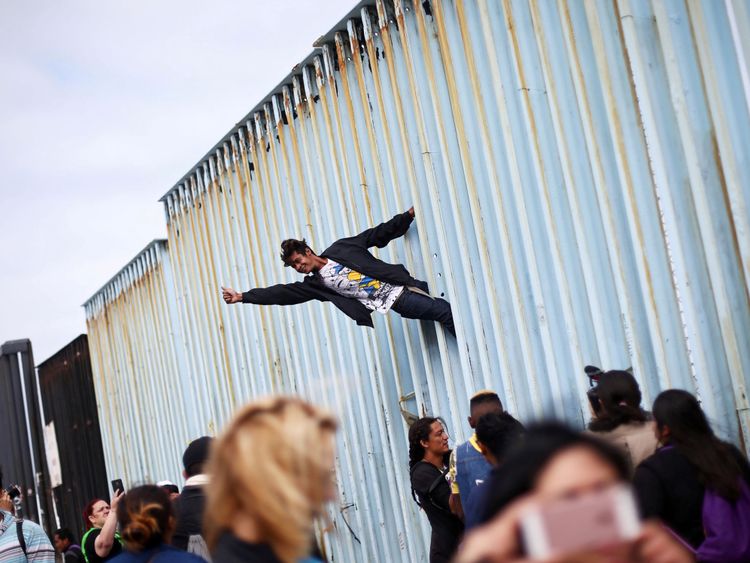  Un homme grimpe la barrière frontalière à l'appui des centaines de migrants centraméricains 