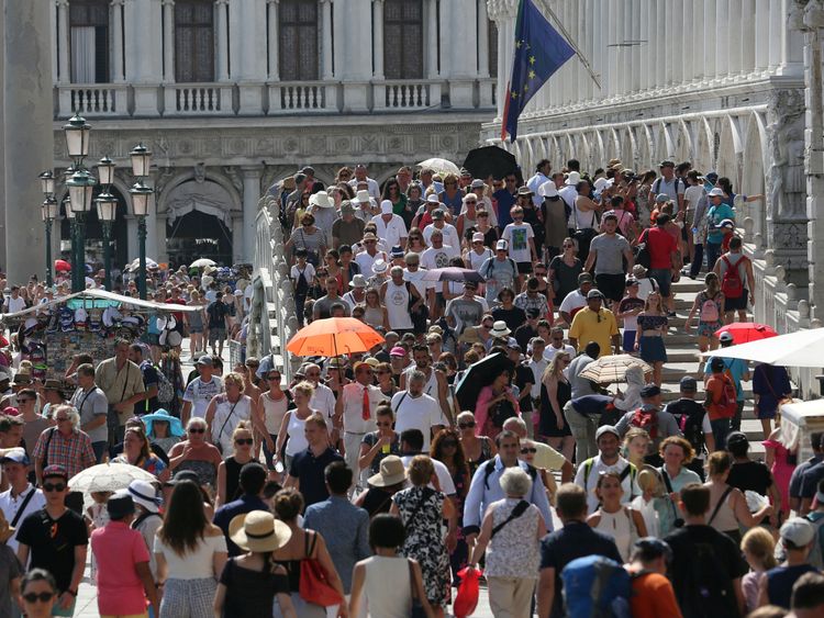 Des touristes marchent près de la place Saint-Marc à Venise, en Italie, le 3 août 2017