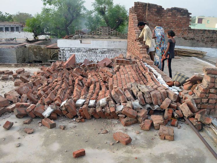  Les résidents indiens regardent un mur endommagé par des vents violents lors d'une importante tempête de poussière dans le district d'Agra, dans le nord de l'Inde, dans l'État d'Uttar Pradesh 