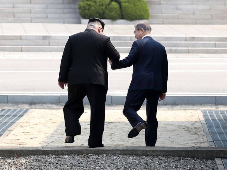  Kim Jong Un (L) prend la main de Moon Jae-in (R) pour franchir la ligne de démarcation 