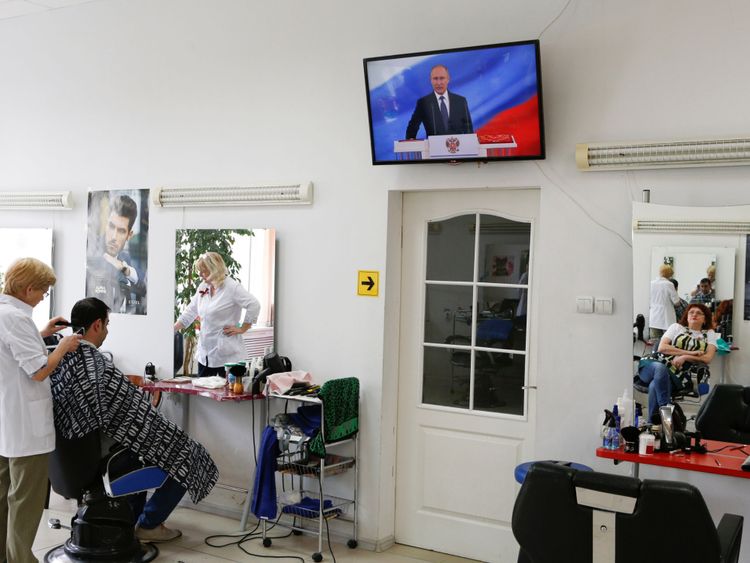  Un coiffeur assiste à l'inauguration de Vladimir Poutine. Président de la Russie, se reflète dans un miroir dans un salon de coiffure à Stavropol, en Russie 7 mai 2018. REUTERS / Eduard Korniyenko 