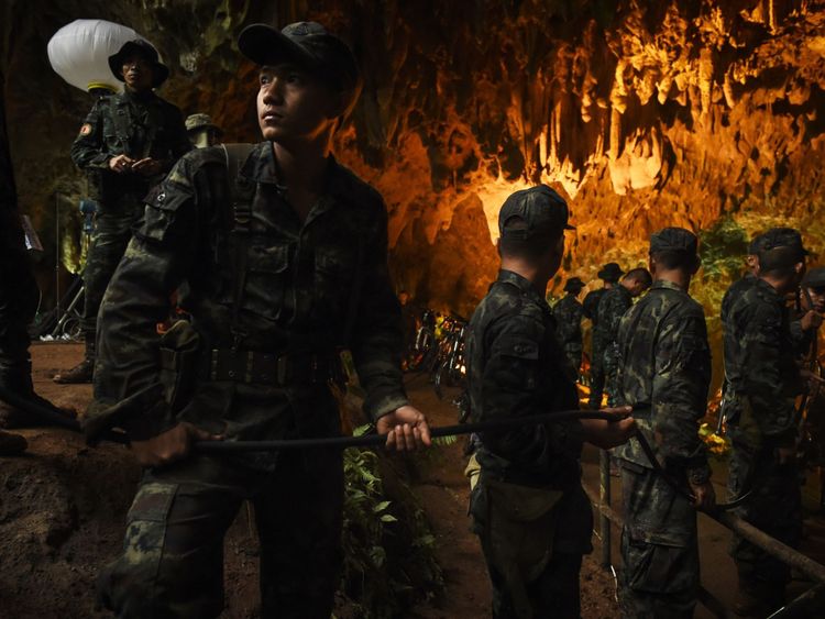 Des soldats thaïlandais relaient un câble électrique dans la grotte de Tham Luang