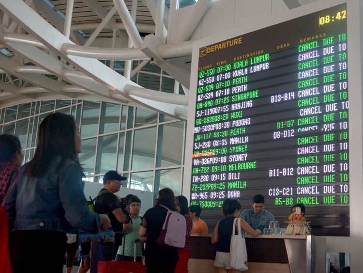 Les voyageurs vérifient leurs vols à l'aéroport Ngurah Rai de Denpasar, Bali, qui est fermé le 29 juin 2018 après qu'un rapport pilote ait détecté des cendres volcaniques s'élevant jusqu'à 23 000 pieds après l'éruption du Mont Agung. - Bali a fermé son aéroport international à la suite d'une éruption volcanique sur l'île de villégiature indonésienne qui a provoqué l'émission de fumée et de cendres épaisses de 2 000 mètres (6 500 pieds) dans l'atmosphère, a indiqué un responsable. (Photo par GEDE ARDIASA / AFP) (Crédit photo devrait lire GEDE ARDIASA / AFP / Getty Images)