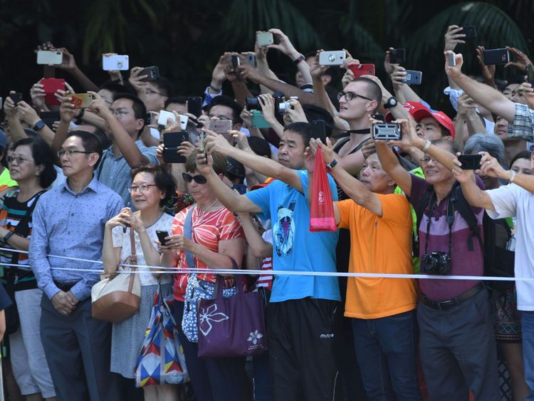  ystanders observent et prennent des photos du cortège transportant le président américain Donald Trump (non représenté) alors qu'il se dirige vers l'Istana, la résidence officielle du Premier ministre singapourien 