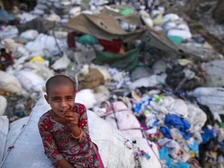 Une fille se trouve parmi les déchets jetés dans un bidonville de Mumbai