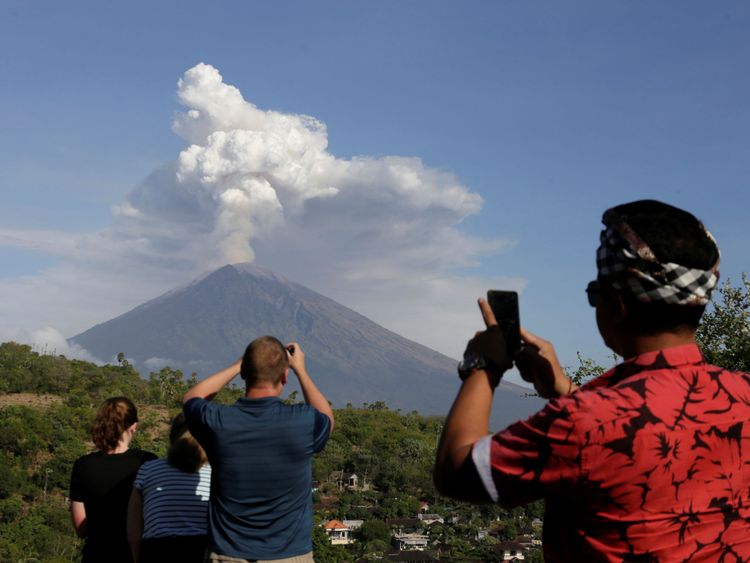 Un guide local et des touristes étrangers prennent des photos du volcan Agung en éruption depuis Amed, Karangasem Regency à Bali, Indonésie le 29 juin 2018. REUTERS / Johannes P. Christo