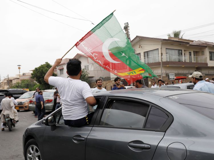 Un partisan du Pakistan Tehreek-e-Insaf (PTI) brandit le drapeau du parti depuis la fenêtre d'une voiture devant un bureau de vote lors des élections générales à Karachi, au Pakistan, le 25 juillet 2018. REUTERS / Akhtar Soomro