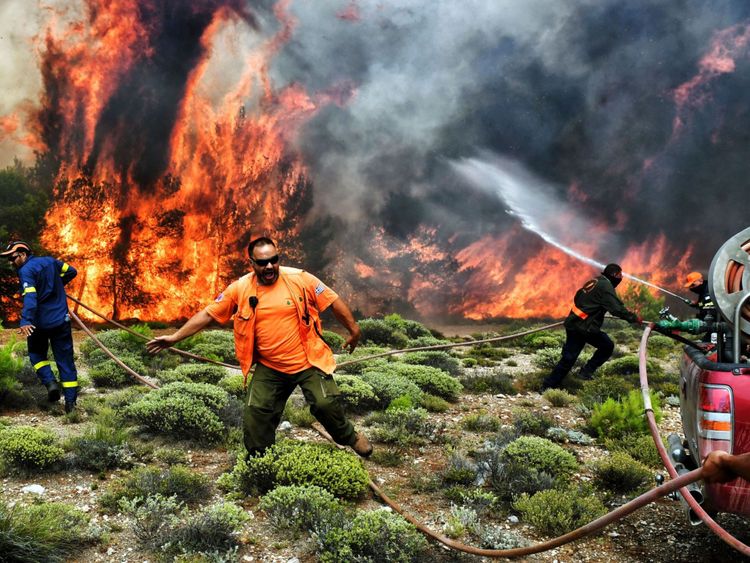 Les pompiers et les volontaires essaient d'éteindre les flammes pendant un feu de forêt dans le village de Kineta, près d'Athènes