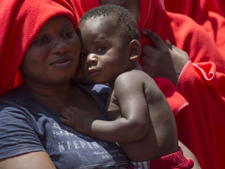 Une femme tient son enfant comme un bateau de la garde côtière espagnole transportant 110 personnes sauvées d'un bateau gonflable dans la mer Méditerranée arrive au port d'Algésiras