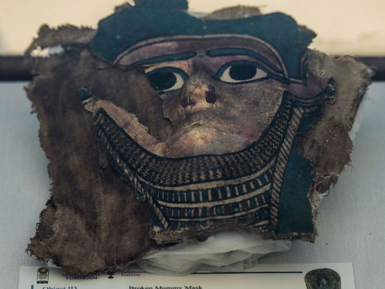 Une photo prise le 14 juillet 2018 montre un masque de momie dorée et brisée exposé devant la pyramide à degrés de Saqqara, au sud de la capitale égyptienne, Le Caire. - Le ministre égyptien des Antiquités a annoncé l'excavation d'un atelier de momification découvert avec un lieu de sépulture communal, composé de plusieurs chambres funéraires. Les travaux sont menés au sud de la pyramide du roi Unas à Saqqarah par une mission égypto-allemande. (Photo par Khaled DESOUKI / AFP) (Crédit photo devrait lire KHALED