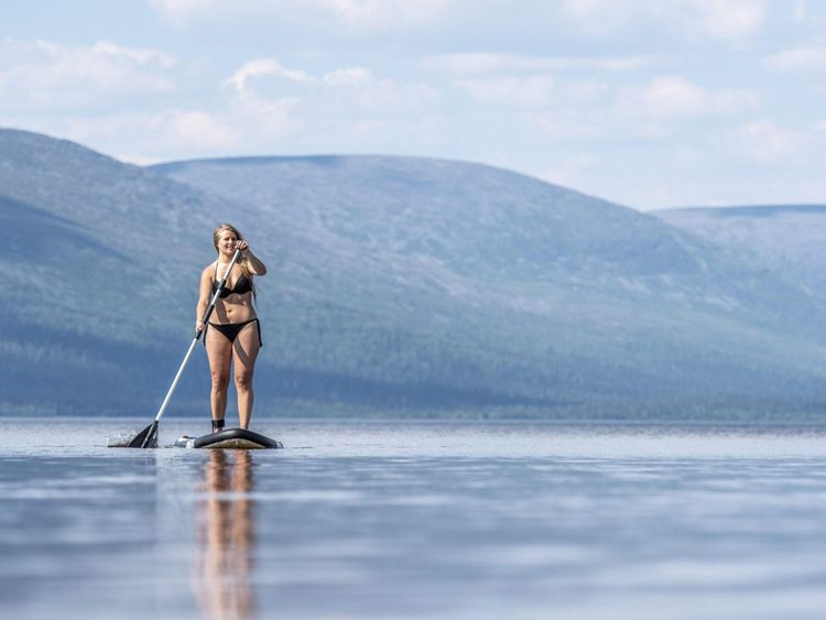 Une femme en bikini sur une planche de surf en Laponie finlandaise