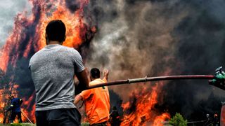 Les pompiers et les volontaires tentent d'éteindre les flammes lors d'un incendie dans le village de Kineta