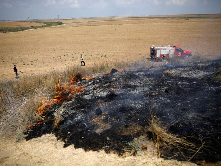 Des pompiers israéliens tentent d'éteindre un feu de brousse dans une région où les Palestiniens causent des flammes en faisant voler des cerfs-volants et des ballons chargés de matériaux inflammables, du côté israélien de la frontière entre Israël et la bande de Gaza 20 juillet