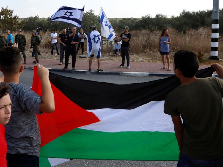 Des Palestiniens se tiennent devant des Israéliens en attendant la libération de l'adolescent palestinien Ahed Tamimi d'une prison israélienne, au poste de contrôle de Rantis en Cisjordanie occupée