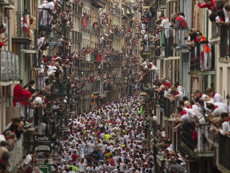 Les gens pendent de leurs fenêtres pour regarder la course des taureaux