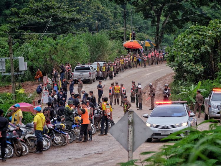 La police s'aligne sur la route menant à la grotte alors que l'opération de secours se poursuit