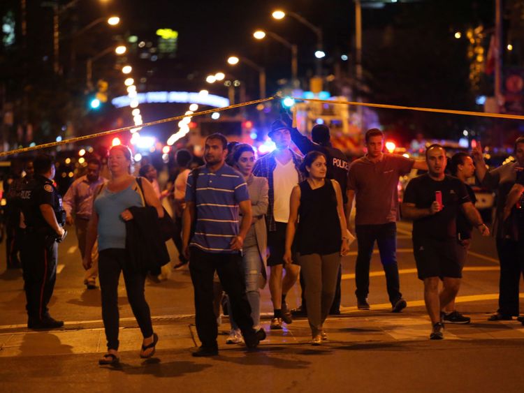 Les gens quittent une zone enregistrée par la police près de la scène d'un tir de masse à Toronto, Canada, 22 juillet 2018