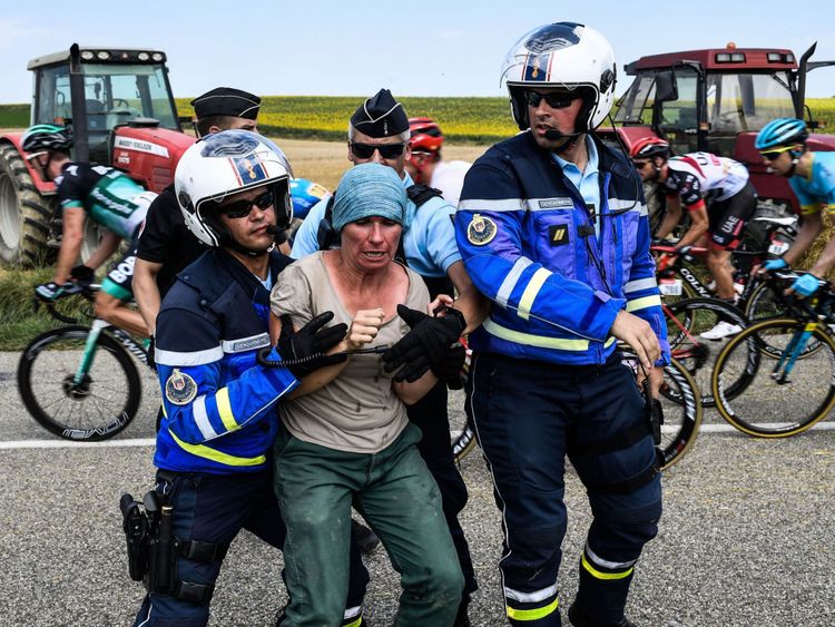 Des gendarmes arrêtent un fermier protestant alors que le peloton se déplace derrière la 16ème étape de la 105ème édition de la course cycliste du Tour de France