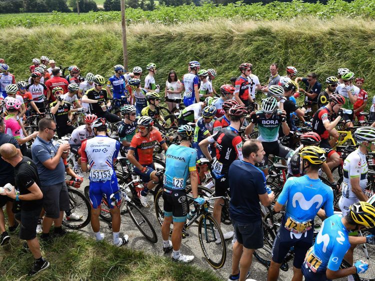 Le groupe de coureurs attend que l'étape reprenne, après que le gaz lacrymogène ait été utilisé pendant une campagne. protestation