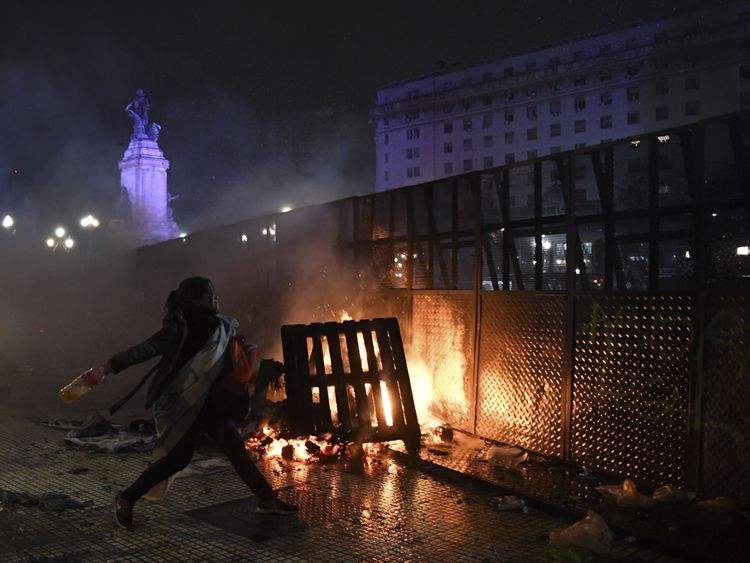 Une femme jette une bouteille à la police à l'extérieur du congrès alors que les manifestants réagissent avec colère au vote