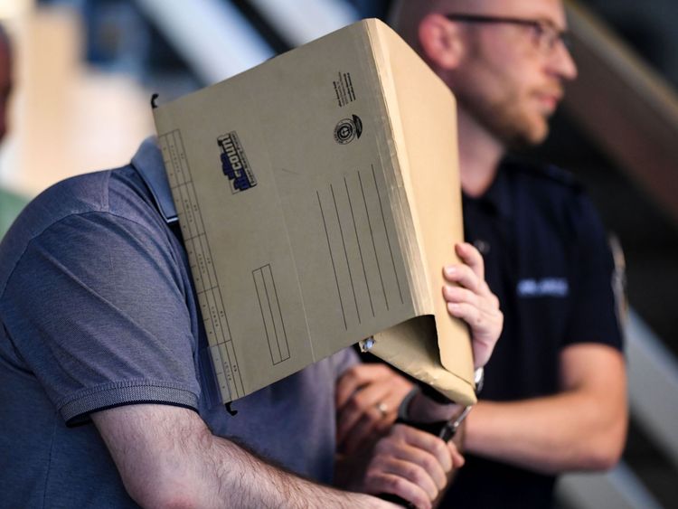 L’inculpé espagnol se couvre le visage en arrivant dans la salle d’audience de Fribourg, dans le sud de l’Allemagne, le 6 août 2018. - Un tribunal allemand a emprisonné l’homme espagnol pendant 10 ans pour avoir abusé sexuellement d’un jeune garçon dont sa mère et son beau-père en ligne (Photo par Patrick Seeger / dpa / AFP) / Allemagne OUT (Crédit photo devrait lire PATRICK SEEGER / AFP / Getty Images)