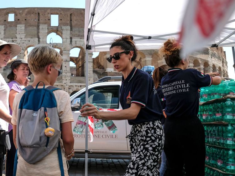 Des membres de la Protection civile italienne (Protezione Civile) distribuent des bouteilles d'eau aux gens et aux touristes devant l'ancien Colisée, au centre de Rome 