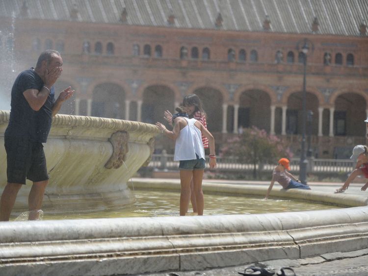 Les gens se rafraîchissent dans une fontaine à la Plaza de España, à Séville