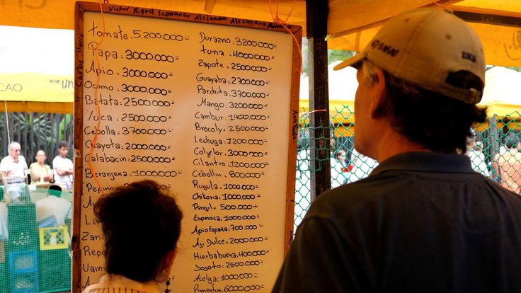 Les gens vérifient les prix des fruits et légumes dans un marché de rue à Caracas, au Venezuela