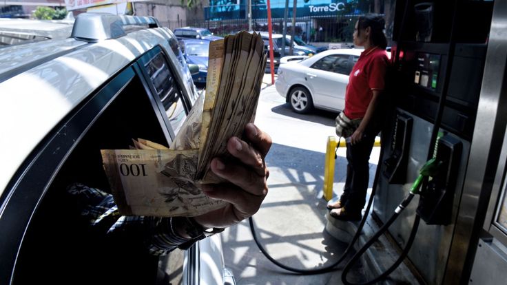 Un client montre des factures Bolivar dans une station-service à Caracas où les gens font la queue pour de l'essence