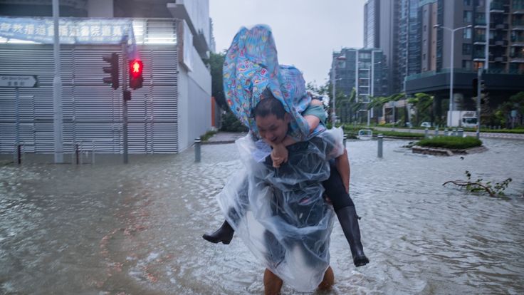 HONG KONG, HONG KONG - 16 SEPTEMBRE: Un homme portant une femme traverse une route inondée le 16 septembre 2018 à Hong Kong, Hong Kong. Les fonctionnaires de la ville ont soulevé l'alerte de tempête à T10, le plus haut niveau, alors que le typhon Mangkhut a atterri sur Hong Kong. La plus forte tempête tropicale de la saison avec des vents atteignant 200 kilomètres à l'heure, Mangkhut aurait tué au moins 25 personnes aux Philippines alors qu'elle continue son chemin vers le sud de la Chine. (Photo de Lam Yik Fei / Getty Images)
